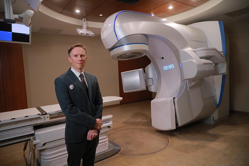 Dr. 大卫·皮尔森站在一台大型医疗放射机前