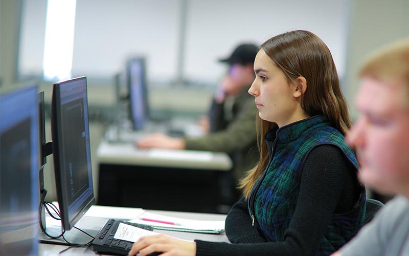 student at a computer lab station observes code