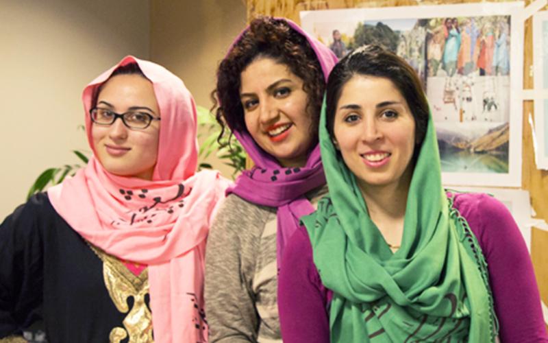 three students each wearing colorful headscarves smile